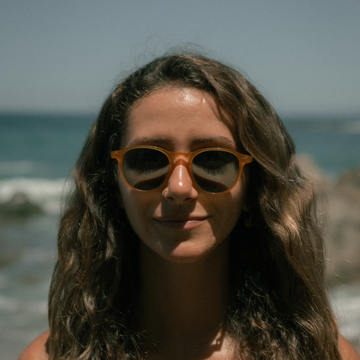 Woman wearing sunglasses with ocean in the background